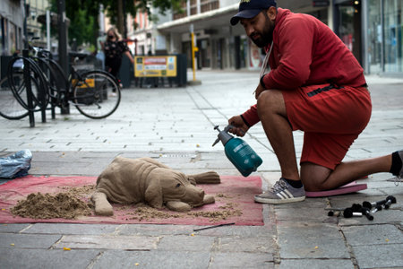 Mulhouse - France - 3 July 2021 - POrtrait of artist sculpting a dog with sand in the streetのeditorial素材