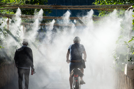 Strasbourg - France - 11 July 2021 - Portrait of people walking in urban park in sprayer installation in front of the train stationのeditorial素材