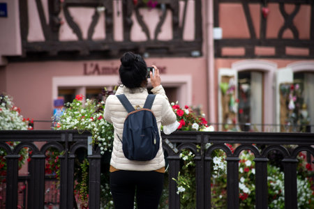 Colmar - France - 28 August 2021 -Portrait on back view of tourist taking a photo with her smartphoneのeditorial素材
