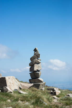 Closeup of stone balance at the top of the mountain on blue sky background