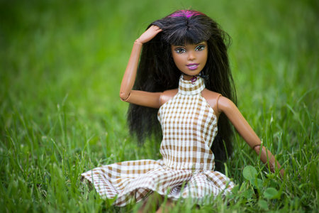 Mulhouse - France - 30 September 2021 - Portrait of black barbie doll wearing a summer dress sitting in a public gardenのeditorial素材