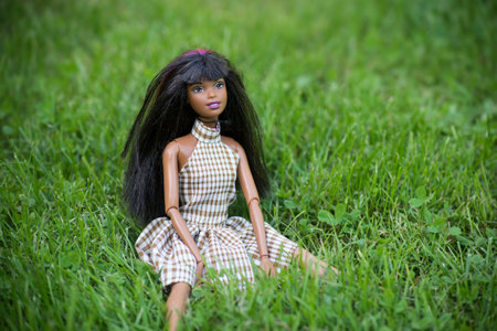 Mulhouse - France - 30 September 2021 - Portrait of black barbie doll wearing a summer dress sitting in a public gardenのeditorial素材