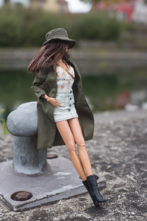 Mulhouse - France - 20 October 2021 - Portrait of brunette barbie doll wearing a blue jeans mini skirt and a green rain coat standing in the streetのeditorial素材