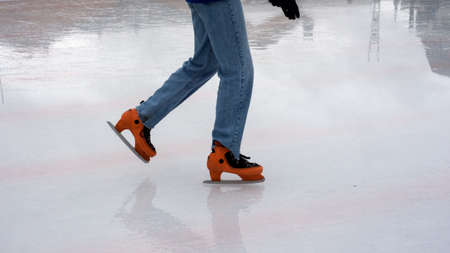Closeup of feet of woman with ice skates on an ice rinkの写真素材