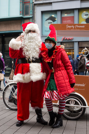 Strasbourg - France - 11 December 2021- Portrait of man and young woman wearing a santa claus and leprechaun costume in the streetのeditorial素材