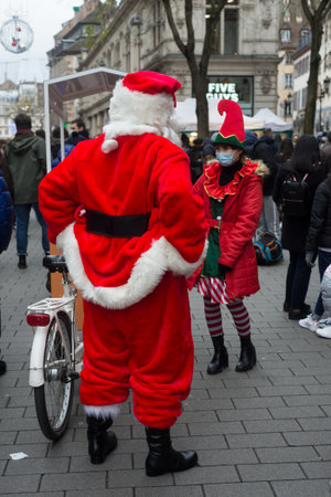 Strasbourg - France - 11 December 2021- Portrait of man and young woman wearing a santa claus and leprechaun costume in the streetのeditorial素材