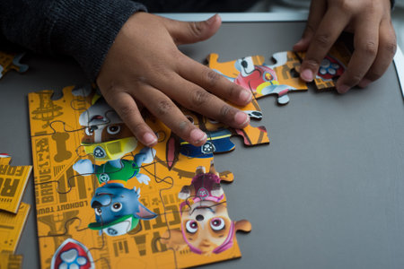 Mulhouse - France - 24 December 2021 - Closeup of hands of african kid making a paw patrol puzzleのeditorial素材