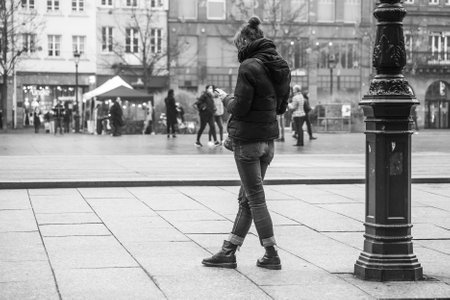 Strasbourg - France - 15 January 2022 - Portrait on back view of young woman standing in the street with her smartphone in handのeditorial素材
