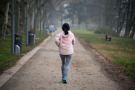Portrait on back view of asian girl running in a public gardenの写真素材