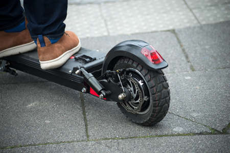 Closeup of feet on electric scooter  waiting to crossing the street