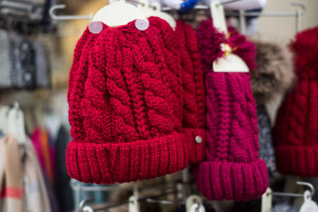 Closeup of red woolen hats on hangers  in the streetの写真素材