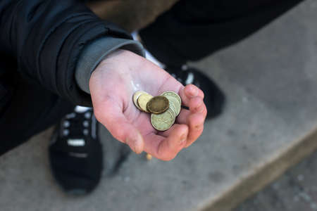 closeup of euros coins in hand of poor man sitting in the streetの写真素材