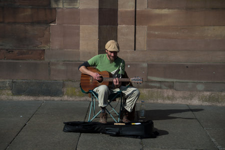 Strasbourg - France - 12 February 2022 - Portait of musician playing guitar in the street by sunny...