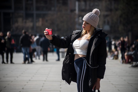 Strasbourg - France - 19 March 2022 - Portrait of sexy girl taking a selfie in the street with her smartphoneのeditorial素材