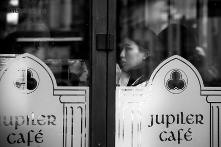 Colmar - France - 2 April 2022 - Portrait of asian woman sitting in the cafe behind a window