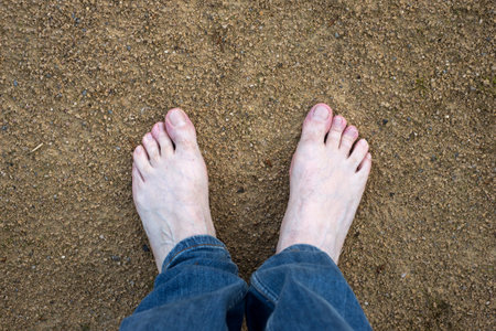 Closeup of barefoot man on the sand surface in outdoor