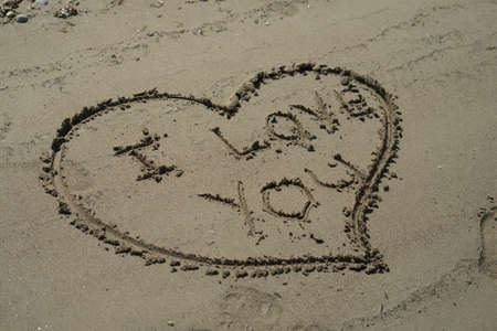 Closeup of heart and I love you text writing on the sand on the beach