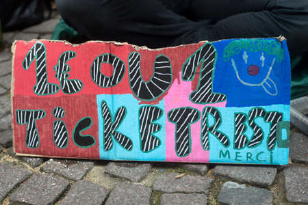 Closeup of homeless placard with text in french : un euro ou un ticket restaurant svp merci, in...