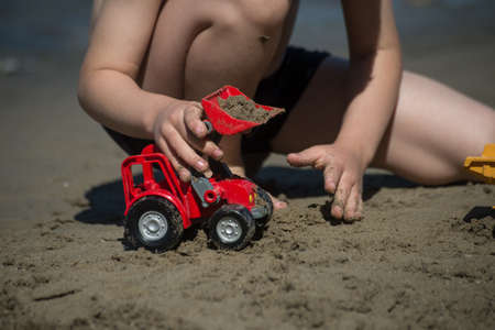 Closeup of hands of kid playing with plastic toys on the beachの写真素材