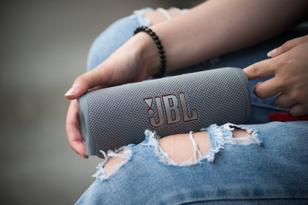 Mulhouse - France - 16 June 2022 - Closeup of grey portable JBL subwoofer speaker in hands of young...