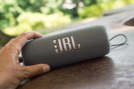 Mulhouse - France - 16 June 2022 - Closeup of grey portable JBL subwoofer speaker in hand in a public gardenのeditorial素材