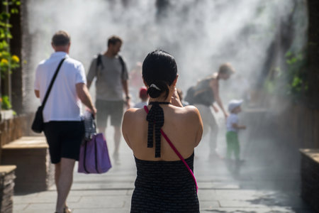 Strasbourg - France - 9 July 2022 - Portrait on back view of young woman taking a photo in sprayer installation at the main placeのeditorial素材