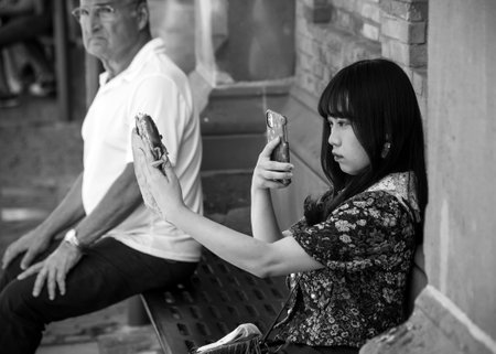 Colmar - France - 12 July 2022 - Portrait of asian tourist with smartphone in the street in black and whiteのeditorial素材