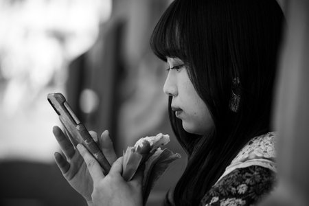 Colmar - France - 12 July 2022 - Portrait of asian tourist with smartphone in the street in black and whiteのeditorial素材