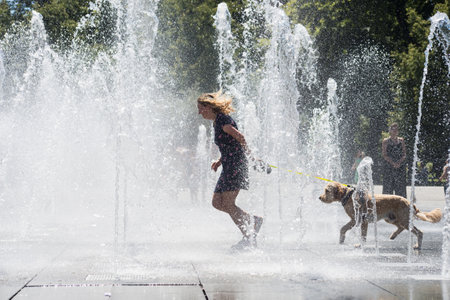Colmar - France - 12 July 2022 - Portrait of woman with dog splashing in a public fountain in the streetのeditorial素材