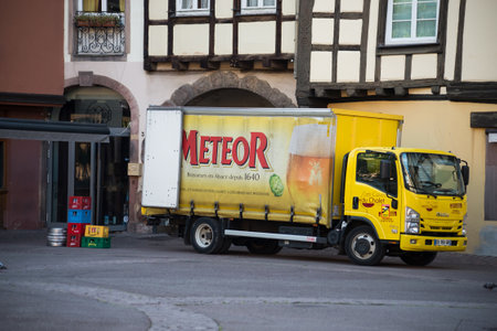 Colmar - France - 12 July 2022 - Profile view of yellow meteor beer truck parked in the street in front of restaurantのeditorial素材