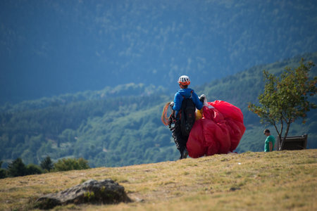 Le grand Ballon - France - 4 August  2022 - portrait on back view of paraglider walking with his wing before the take offのeditorial素材