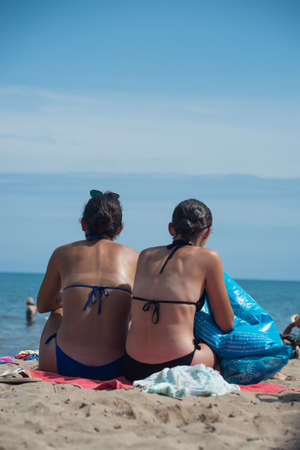 Valras - France - 28 July 2022 - Portrait of two girls wearing bikini sitting on the beachの写真素材