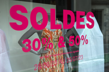 closeup of discount sign "SOLDES up to 30%, 50%" in french, the translation of (sales until 30% , 50%) on window in french fashion store showroom on summer clothes backgroundの写真素材