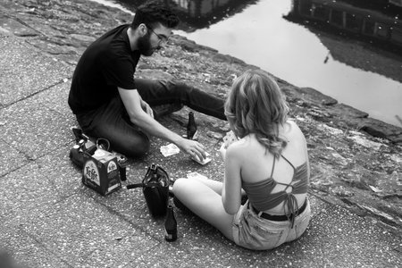 Strasbourg -France - 29 August 2023 - couple of young people playing with cards sitting in border the water in little France quarterのeditorial素材
