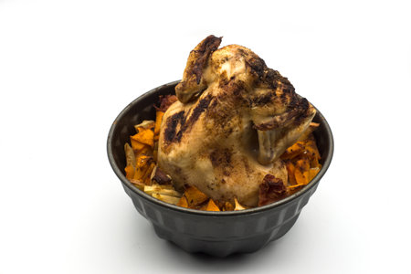 Closeup of cooked chicken with potatoes in a grey bowl on white backgroundの写真素材