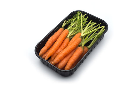 group on mini carrots in a plastic tray on white backgroundの写真素材