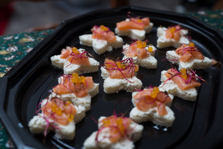 Closeup of appetizers toast with salmon and lumpfish roe in a black plateの写真素材