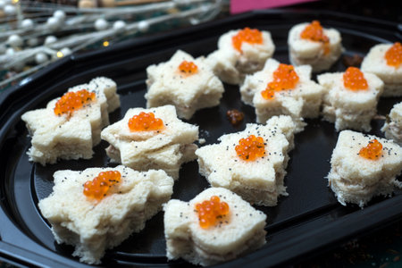Closeup of appetizers toast with salmon and lumpfish roe in a black plateの写真素材