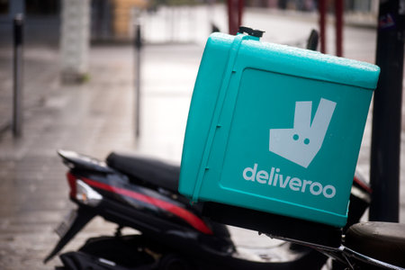 Mulhouse - France - 25 february 2024 - Closeup of deliveroo logo on blue plastic backpack on motorcycle parked  in the streetのeditorial素材