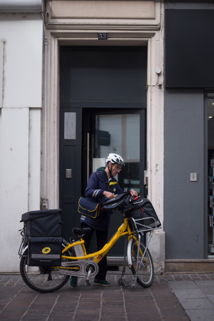 Mulhouse - France - 14 April 2024 - portrait of post man standing near his bicycle in the streetのeditorial素材
