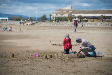 Gruissan - France - 27 April 2024 - portrait of man and boy making a sand castle on the beachのeditorial素材