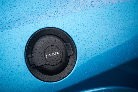 closeup of rain drops of fuel hatch on blue car parked in the street