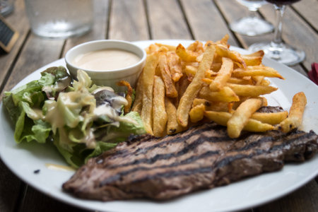 closeup of beefsteak, french fries and salad at the restaurantの写真素材