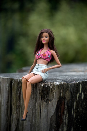 Quimper - France - 13 July 2024 - Portrait of brunette barbie doll sitting in a public gardenのeditorial素材