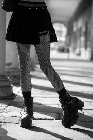 Closeup of legs of gothic girl wearing sexy stockings and black boots standing in the streetの写真素材