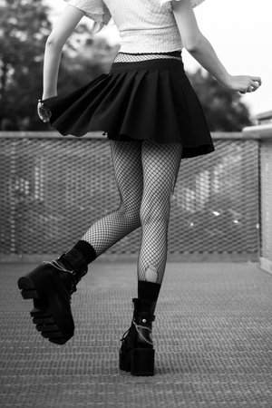 Closeup of legs of gothic girl wearing sexy stockings and black boots standing in the streetの写真素材