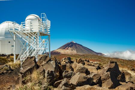 International observatory in Teide National Park. Volcano Teide on the backgriund. Windy day with clouds and amazinc colors. Technology science concept.の写真素材