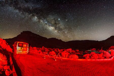 Shot of stars and milky way at hight sky, fish eye lens. Two telescopes ready for observation lit by the rear lights of the car in foreground.. No Moon. Long Exposure. National Park Teide, Tenerife.の写真素材