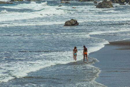 Benijo, Tenerife, Spain - June 22, 2015: Natural sand beach. Popular place for local people and tourists. Volcanic rocks billowi out of turquoise water and soft gentle waves washing the sandy shore.のeditorial素材