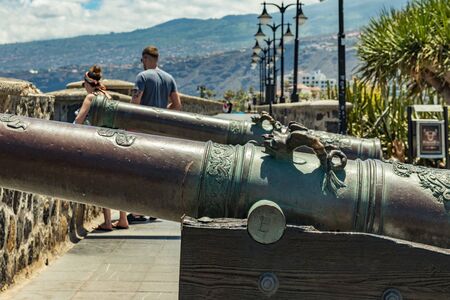 Puerto de la Cruz, Tenerife, Spain - July 10, 2019: . The Old port of town is a popular tourist attraction and favorite place for the locals. Old fortress guns to protect the harbor.のeditorial素材